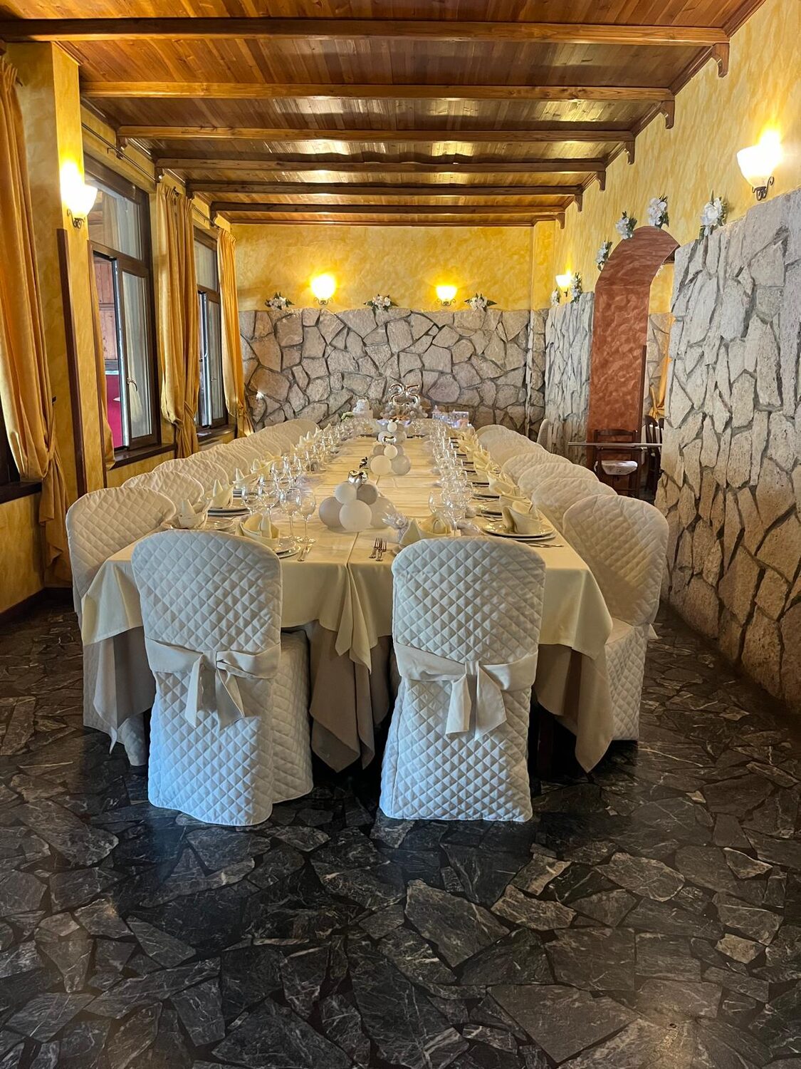 Sala interna con parete in pietra e soffitto in legno, tavolo imperiale apparecchiato — Le Colombe Da Tiziano
